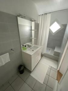 a white bathroom with a sink and a shower at Chambre bordée par le GR34 in Sibiril