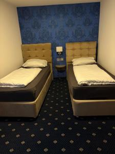 two beds in a room with blue walls at WaldGold Aparthotel in Nagold