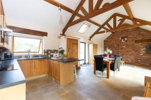 a kitchen with wooden cabinets and a dining room with a table at Blackberry Barn in Wotton-under-Edge