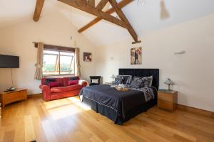 a bedroom with a bed and a couch and a tv at Blackberry Barn in Wotton-under-Edge