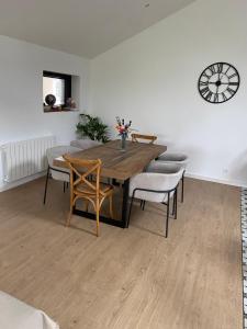a dining room table with chairs and a clock on the wall at Chambre bordée par le GR34 in Sibiril