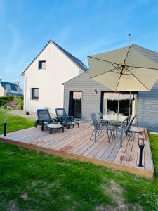 a wooden deck with a table and an umbrella at Chambre bordée par le GR34 in Sibiril