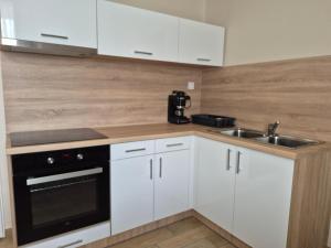 a kitchen with white cabinets and a sink at Kriszta Gold Vendégház in Újfehértó