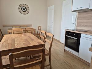 a kitchen with a table and chairs and a clock on the wall at Kriszta Gold Vendégház in Újfehértó