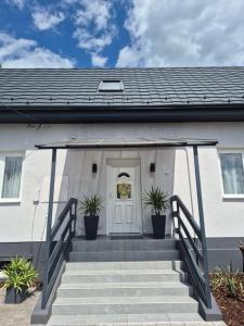 a white house with a white door and stairs at Kriszta Gold Vendégház in Újfehértó +6 photos