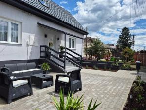 a patio with chairs and a bench and a house at Kriszta Gold Vendégház in Újfehértó