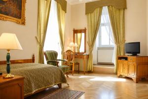 a bedroom with a bed and a desk with a television at Bristol Vila Tereza in Karlovy Vary