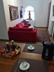 a living room with a red couch and a table at Stemnitsa Stone Residence - Cosy Mountain Escape in Stemnitsa