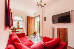 a living room with a red couch and a tv at Stemnitsa Stone Residence - Cosy Mountain Escape in Stemnitsa