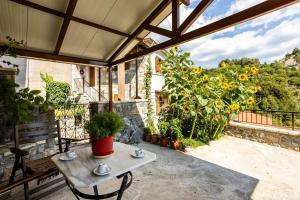 a patio with a table and a bunch of sunflowers at Stemnitsa Stone Residence - Cosy Mountain Escape in Stemnitsa +26 photos