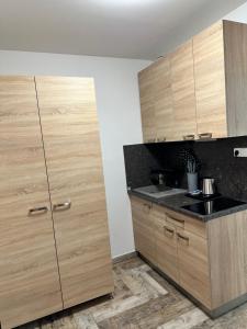 a kitchen with wooden cabinets and a sink at Apartmány Sladký sen in Kežmarok
