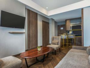 a living room with a table and chairs and a tv at Mercure Jayapura in Jayapura