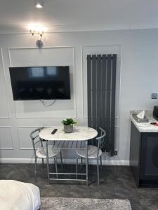 ein Zimmer mit einem Tisch, Stühlen und einem Fernseher in der Unterkunft awesome studio flat in Welling