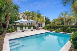 a swimming pool in front of a house with palm trees at A Wave From It All - 811 Ocean Blvd in Saint Simons