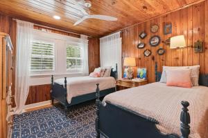 a bedroom with two beds and a window and wooden walls at A Wave From It All - 811 Ocean Blvd in Saint Simons +36 photos