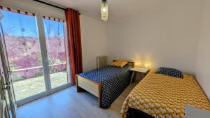 two beds in a room with a window at Maison du cèdre in Bonnac-la-Côte