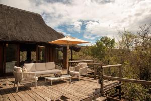 a wooden deck with chairs and an umbrella at Tshwene Lodge in Vaalwater