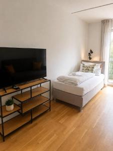a bedroom with a bed and a tv and a table at Salí Homes R4 - High-Quality Apartment with Terrace in Bayreuth
