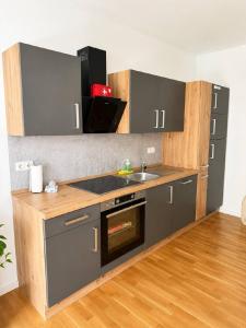 a kitchen with gray cabinets and a sink and a stove at Salí Homes R4 - High-Quality Apartment with Terrace in Bayreuth +19 photos