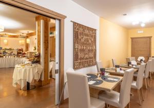 a dining room with a table and white chairs at Adler ApartHotel in Moena