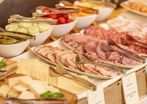 a table filled with different types of meats and cheeses at Adler ApartHotel in Moena