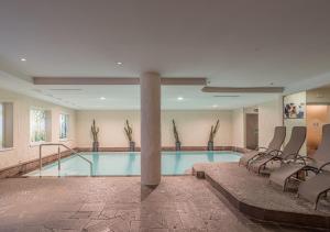 a swimming pool in a hotel room with chairs at Adler ApartHotel in Moena +16 photos