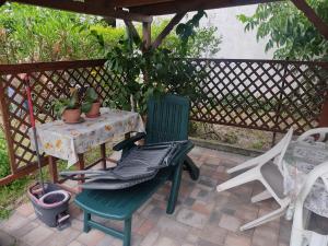 a green chair sitting next to a table with a plant at Pipacs ház in Balatonlelle