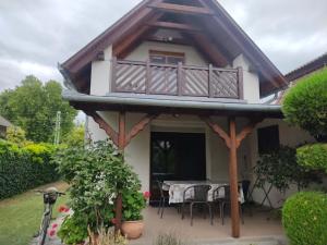 a house with a balcony and a table at Pipacs ház in Balatonlelle