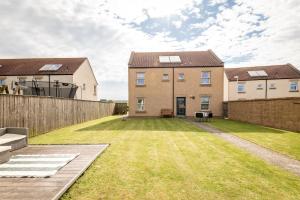 a yard with two houses and a fence at The View, 22 School Park in Kingsbarns