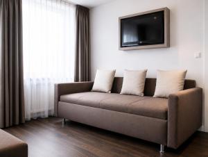 a living room with a couch and a tv at Manhattan Hotel in Frankfurt