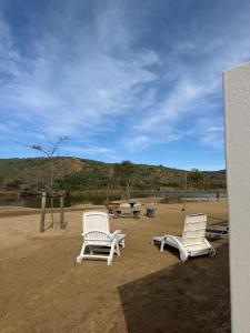 two white chairs and a picnic table in the sand at LTB-Waterkant Cottage in Malgas