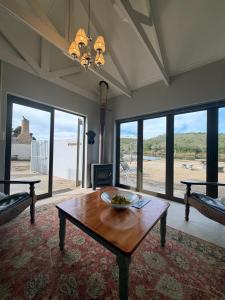 a living room with a table and large windows at LTB-Waterkant Cottage in Malgas