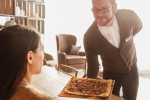 a man is holding a box of pizza on a table at IntercityHotel Braunschweig in Braunschweig