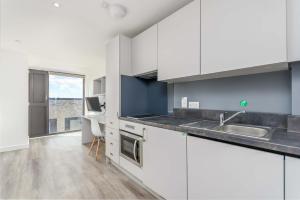 a kitchen with white cabinets and a sink at Modern Studios in Central Coventry in Coventry