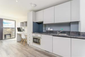 a kitchen with white cabinets and a large window at Modern Studios in Central Coventry in Coventry