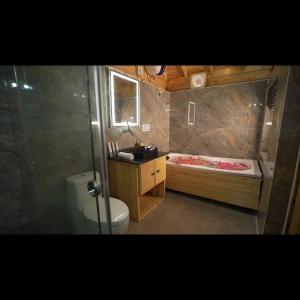 a bathroom with a tub and a toilet and a sink at KPHB Wooden Cottages in Hyderabad
