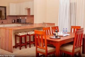 a kitchen with a wooden table with chairs and a counter at Kris Star Lodge in Blantyre