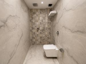 a bathroom with a toilet and a stone wall at Hotel Beverly Palace Santacruz - Near BKC - Mumbai Airport T1 in Mumbai