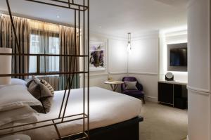a hotel room with a bed and a chair at The Guardsman Hotel in London