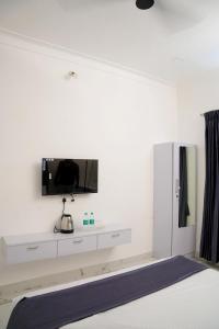 a bedroom with a tv on a white wall at La Maison Du Bonheur in Pondicherry