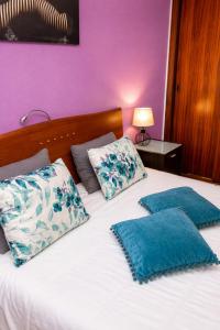 two pillows on a bed with a purple wall at Spot Matur Apartment in Machico