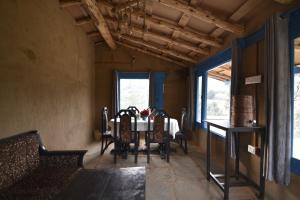a dining room with a table and chairs and windows at Idyllic Haven Heritage, Jageshwar in Jageshwar