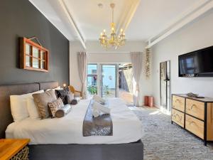 a bedroom with a large bed and a chandelier at Salt Boutique Guest House in Bloubergstrand