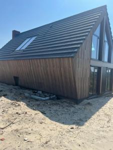a large wooden building on top of a beach at De Duyn in Midsland