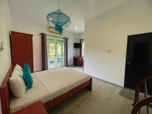 a bedroom with a bed and a tv and a room at Nandawanam Guest House Pasikuda in Kalkudah