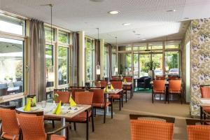 a restaurant with tables and chairs and windows at GDA Hotel Göttingen in Göttingen
