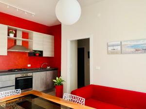 a red living room with a red couch and a kitchen at Maria Pia's home in Marotta
