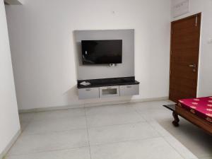 a living room with a tv on a white wall at Green fields in Vijayawāda