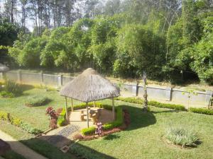 a gazebo with a straw roof in a garden at Dimi HOUSE in Andasibe