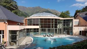 a large building with a swimming pool in front of it at Chalet Bruyère in Cauterets